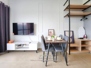 a dining room with a table and chairs and a tv at Mossaz at Empire Damansara by Wodages in Kuala Selangor