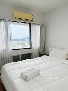 a bedroom with a large white bed with a window at 2BR Comfy Family Suite Hat Yai in Hat Yai
