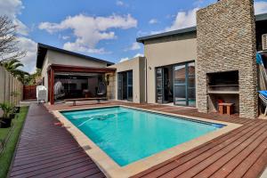 a swimming pool on a wooden deck next to a house at House of Bongekile 4 Bed Luxury Home in Malelane in Malelane