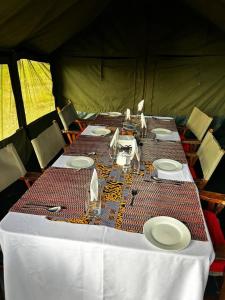 a table in a tent with plates and napkins at Sadanga & Sons Mobile Camp Safaris in Mugumu