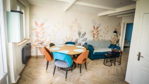 a dining room with a table and chairs and a couch at Maison calme éventail de Cabourg in Cabourg