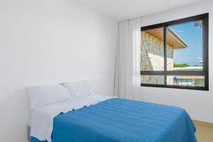 a bedroom with a blue and white bed and a window at GB110 Village Duplex 4 Suítes - Guarajuba in Monte Gordo +40 photos