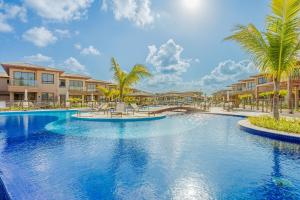 a swimming pool at a resort with palm trees and condos at GB110 Village Duplex 4 Suítes - Guarajuba in Monte Gordo