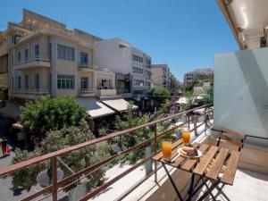 a balcony with a table and two glasses of orange juice at Heraklions Heart Apartment in Heraklio Town