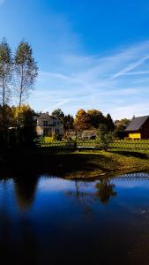 a body of water with a house in the background at Bieszczady Domek Letniskowy in Polańczyk