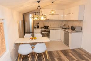 a kitchen with a table and some white chairs at Cozy Modern Apartment in Gevgelija +8 photos