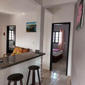 a kitchen with a counter and two stools in a room at Moradas Jeane in Guarda do Embaú