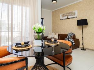 - un salon avec une table en verre et des chaises orange dans l'établissement Anna Suite - Serenity & Stuff Luxury Apartments, à Midrand