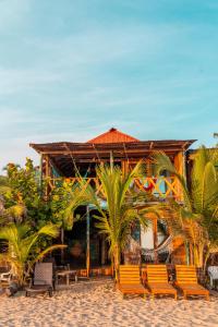 a building on the beach with chairs and palm trees at the mompe beach hostal in La Poza