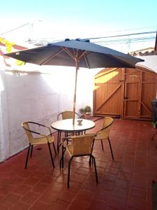 ラ・セレナにあるAlojamiento en La Serena con estacionamientoのパティオに置かれたテーブルと椅子、そして傘