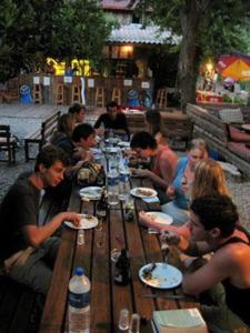 a group of people sitting around a long wooden table at Bayrams Tree Houses in Olympos