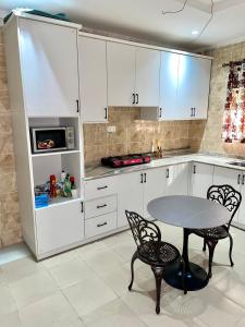 a kitchen with white cabinets and a table and chairs at Bilak Luxury Apartments & Homes Ltd in Abuja