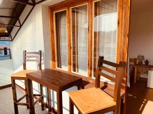 a wooden table and chairs in front of a window at Vita Stulba Guest House in Sandanski