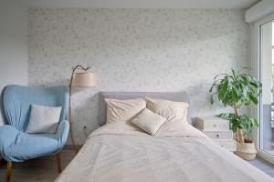 a bedroom with a bed and a blue chair at Le cocon bohème chic in Sartrouville