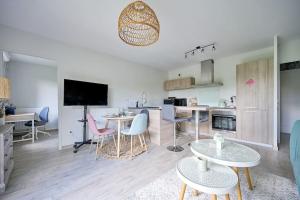a living room with tables and chairs and a kitchen at Le cocon bohème chic in Sartrouville +8 photos