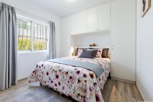 a white bedroom with a bed with a floral bedspread at Amantes del Mar, Heated pool in Costa Del Silencio +28 photos