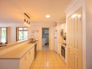 a large kitchen with white cabinets and a hallway at Peaceful 4B2B Sweet Home w Backyard at Springfield in Springfield Lakes