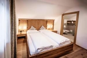 ein Schlafzimmer mit einem großen Bett und einem großen Spiegel in der Unterkunft Wonga Apartments in Gais