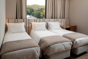 本图贡萨尔维斯Plaza Hotel & Boulevard Convention - Vale dos Vinhedos的带窗户的酒店房间里有两张床