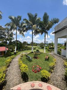 a park with palm trees and benches and flowers at Finca Hotel Andaquies in Armenia