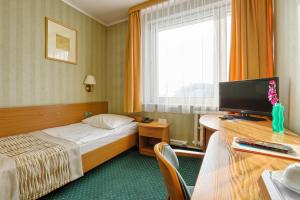 a hotel room with a bed and a desk with a television at Hotel Festival in Opole