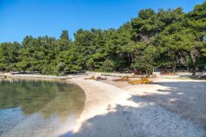 ヴルボスカにあるApartments Peaceの砂浜と水面にテーブルと椅子が置かれたビーチ