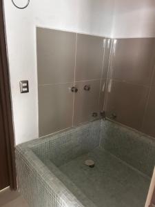 a bathroom with a shower with a green tiled tub at Hermoso Penthouse in Tuxtla Gutiérrez +25 photos