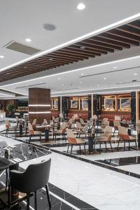 a restaurant with tables and chairs in a building at GRAND SAPPHIRE HOTEL CASINO and RESIDENTS 1 Bedroom Suit with Superior Sea View and Free Internet in Áyios Yeórgios