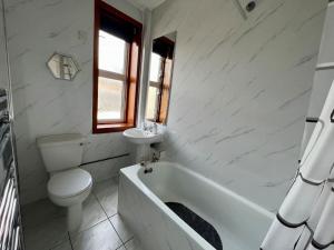 a white bathroom with a toilet and a tub and a sink at Charming Seaside home Sleeps 4 with free parking in Broughty Ferry