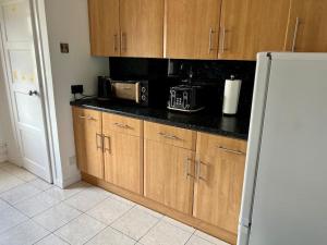a kitchen with wooden cabinets and a refrigerator at Charming Seaside home Sleeps 4 with free parking in Broughty Ferry +4 photos