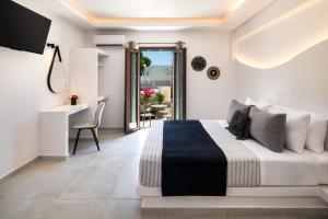 费拉Santorinn Suites Fira的一间带床、书桌和阳台的卧室