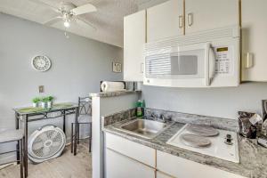 a kitchen with a sink and a microwave at Daytona Beach Condo with Balcony 5 Mi to Speedway! in Daytona Beach
