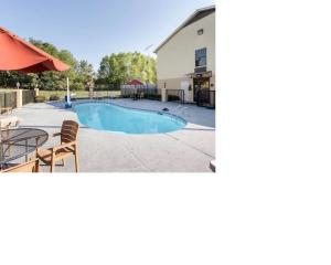 a swimming pool with chairs and a table and an umbrella at Quality Inn Olive Branch - Memphis South in Olive Branch