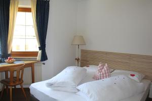uma cama com almofadas brancas, uma secretária e uma janela em Villa Malus em Castelbello