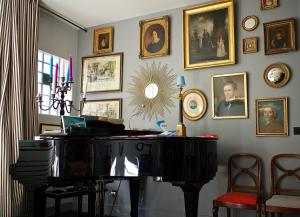 a room with a piano and portraits on the wall at Villa du Square, Luxury Guest House in Paris