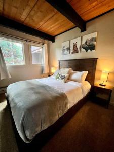 Un dormitorio con una cama grande y dos ventanas. en Condo Adjacent Nordic Ski, Fireplace & Indoor Pool, en Big Sky Meadow Village