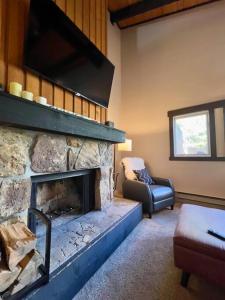 Una sala de estar con una chimenea de piedra y una silla. en Condo Adjacent Nordic Ski, Fireplace & Indoor Pool, en Big Sky Meadow Village