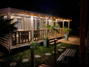 雷日卡普费雷Mobil home 3 chb tout confort, Espace Enfants - Claouey Cap Ferret的木屋,晚上有甲板