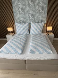 un letto con due cuscini sopra con due comodini di FeWo Meeresblick SPO a Sankt Peter-Ording