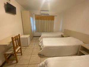a hotel room with three beds and a television at Hotel Blanner in Charqueadas +3 photos