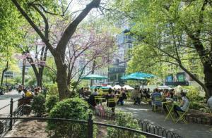 a group of people sitting at tables in a park at Heart of Downtown Manhattan - Stylish One Bedroom Apartment in Vibrant Union Square in New York