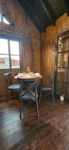 a table and chairs in a room with wooden walls at Recanto AlceNegro in Miguel Pereira