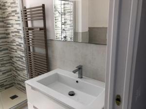 Un lavabo blanco en un baño con espejo. en Taormina loview, en Giardini Naxos