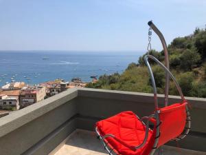 Una bolsa roja colocada en un balcón con vista al océano. en Taormina loview, en Giardini Naxos