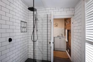 a bathroom with a shower with white tiled walls at Table Hill Cottage - dog friendly retreat in Daylesford +12 photos