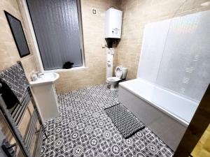 a bathroom with a tub and a sink and a toilet at Stay Sleep Rest - Oldham in Oldham