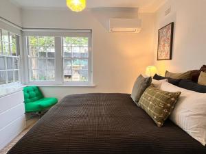a bedroom with a large bed and a green chair at Sunny Retro Home Burnside area in Rose Park