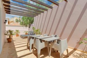 a patio with a table and white chairs at Balancal Apartments and Villas Palheiro Village by Holiday Rental Madeira in Funchal