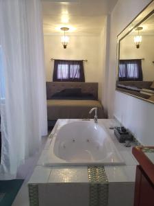 ein Bad mit einer Badewanne, einem Bett und einem Spiegel in der Unterkunft DB Tower Vacation Rental in Belize City