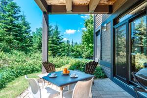 a patio with a blue table and chairs on a house at Lakefront and Mountain View - Resort Studio in Lac-Superieur